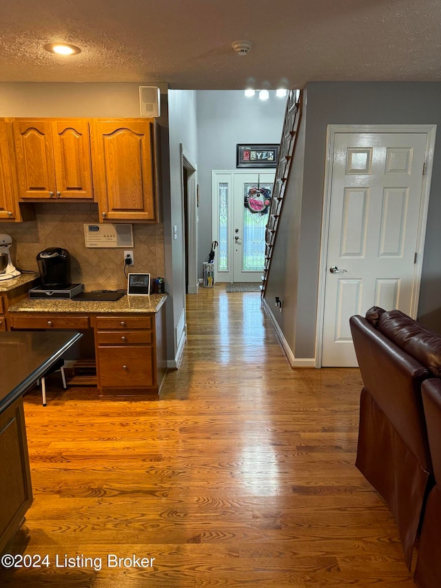 kitchen featuring a textured ceiling, backsplash, and light hardwood / wood-style flooring