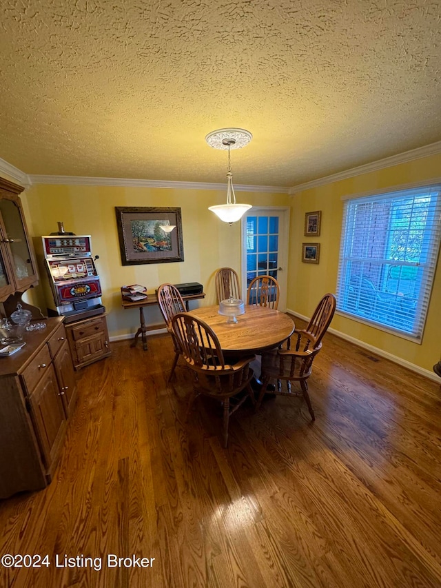 dining space featuring ornamental molding, a textured ceiling, and dark wood-type flooring