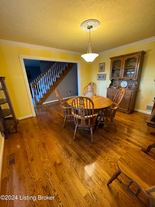 dining area with ornamental molding, a textured ceiling, and dark wood-type flooring