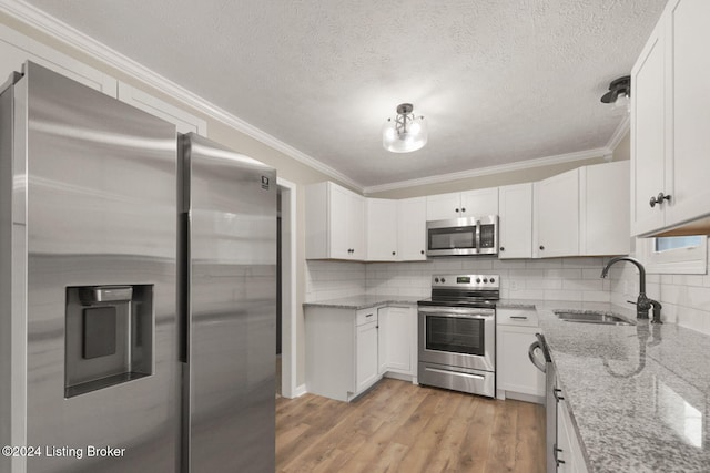 kitchen with light stone countertops, white cabinetry, sink, appliances with stainless steel finishes, and light wood-type flooring