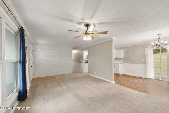 carpeted empty room with ceiling fan with notable chandelier, a textured ceiling, and crown molding