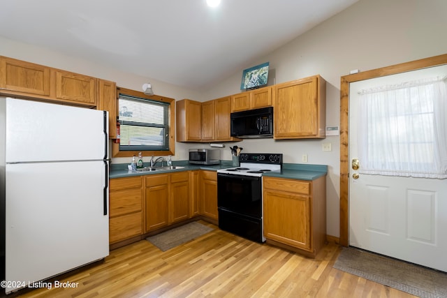 kitchen with black appliances, lofted ceiling, light wood-type flooring, and sink