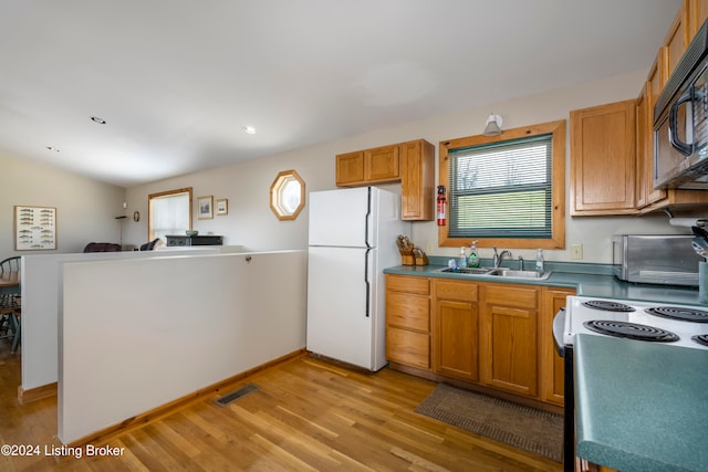 kitchen with stove, light hardwood / wood-style floors, vaulted ceiling, sink, and white fridge