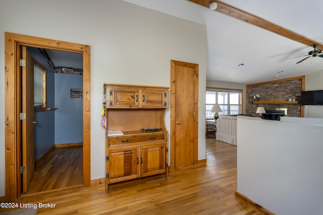 hallway with light wood-type flooring and lofted ceiling with beams