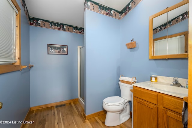 bathroom featuring wood-type flooring, vanity, toilet, and walk in shower