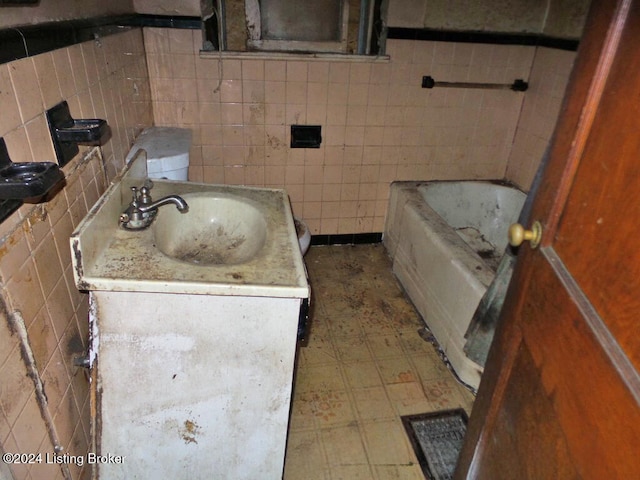 bathroom featuring a washtub, tile walls, and vanity