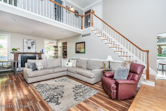 living room with crown molding, a fireplace, a high ceiling, and hardwood / wood-style flooring