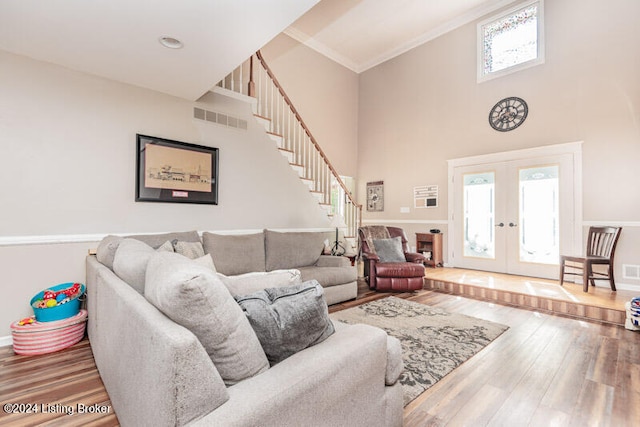 living room with french doors, hardwood / wood-style floors, a high ceiling, and ornamental molding