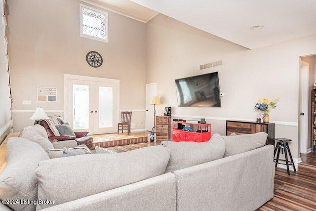 living room featuring hardwood / wood-style floors, a towering ceiling, and french doors