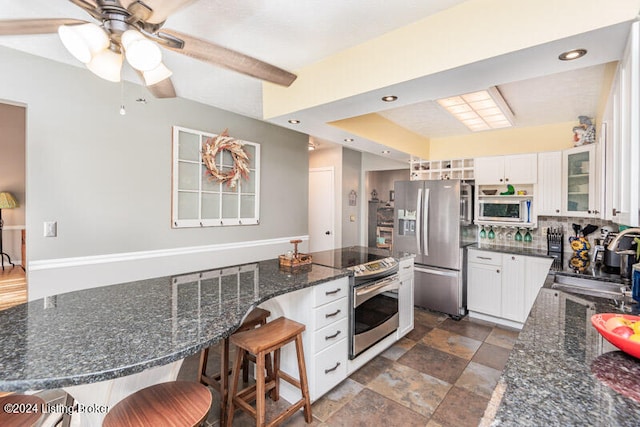 kitchen with a breakfast bar, stainless steel appliances, white cabinetry, and sink