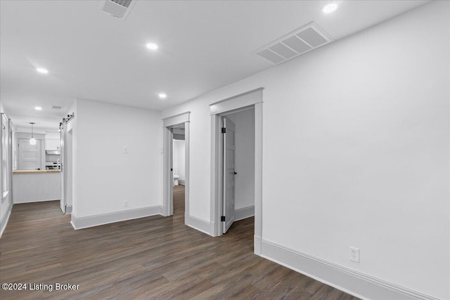 empty room with a barn door and dark hardwood / wood-style flooring