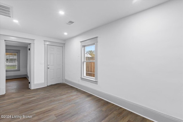 unfurnished bedroom with a closet, dark wood-type flooring, and multiple windows