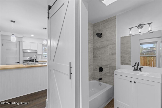 bathroom featuring hardwood / wood-style floors, vanity, and tiled shower / bath