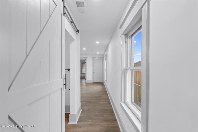 hallway featuring a barn door and dark hardwood / wood-style floors