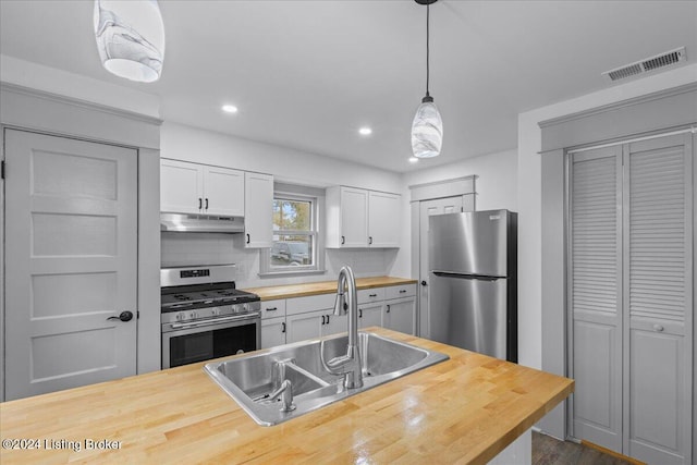 kitchen featuring wooden counters, sink, hanging light fixtures, decorative backsplash, and appliances with stainless steel finishes