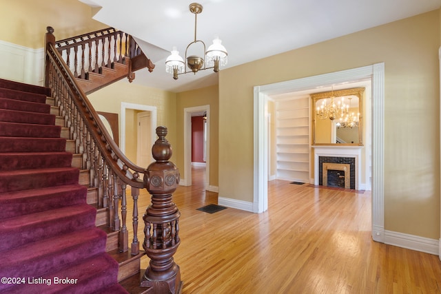 foyer with a notable chandelier, wood-type flooring, and a fireplace