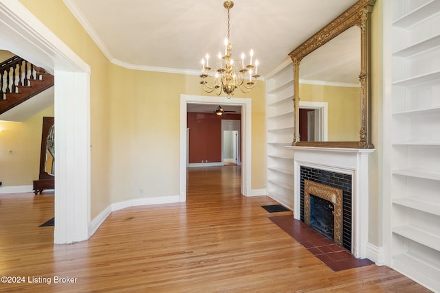 unfurnished living room with wood-type flooring, an inviting chandelier, built in features, and crown molding