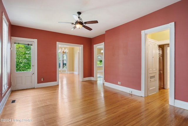 interior space with ceiling fan with notable chandelier and light wood-type flooring