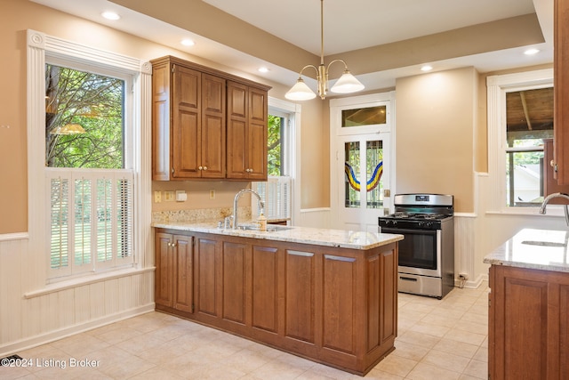 kitchen featuring pendant lighting, an inviting chandelier, stainless steel range with gas cooktop, sink, and kitchen peninsula