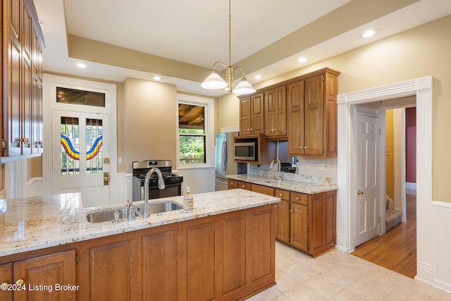 kitchen featuring pendant lighting, sink, light stone countertops, stainless steel appliances, and a chandelier