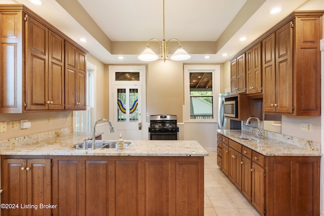 kitchen featuring kitchen peninsula, stainless steel gas range oven, sink, and decorative light fixtures