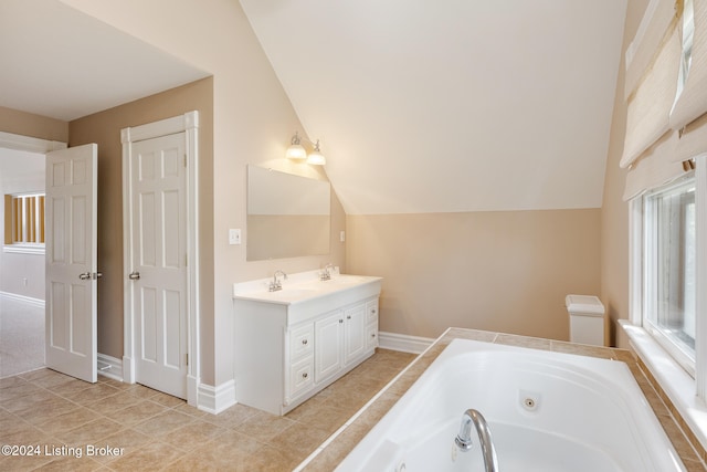 bathroom featuring tile patterned floors, vanity, a tub, and vaulted ceiling