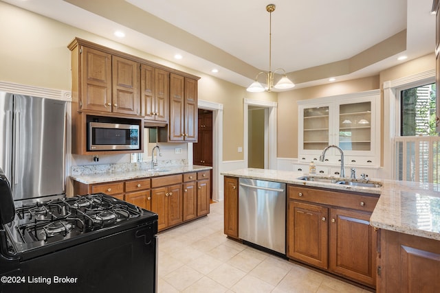 kitchen with light stone countertops, stainless steel appliances, an inviting chandelier, and sink