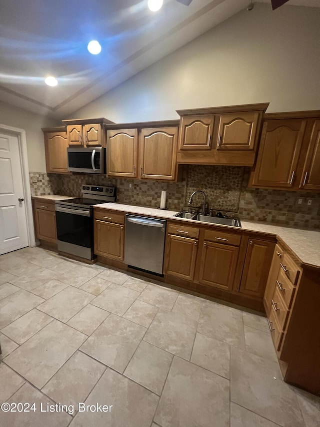 kitchen featuring decorative backsplash, appliances with stainless steel finishes, lofted ceiling, and sink