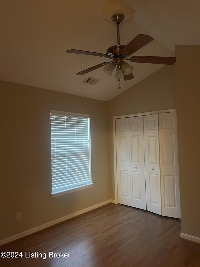 unfurnished bedroom with a closet, ceiling fan, dark hardwood / wood-style flooring, and lofted ceiling