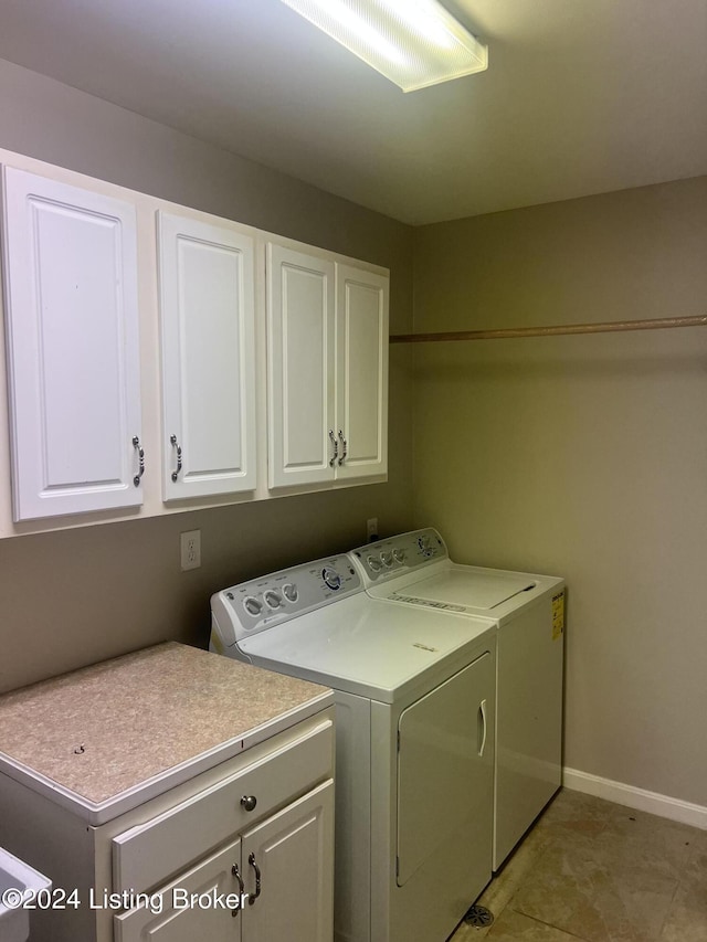 laundry room with cabinets, light tile patterned floors, and washing machine and dryer