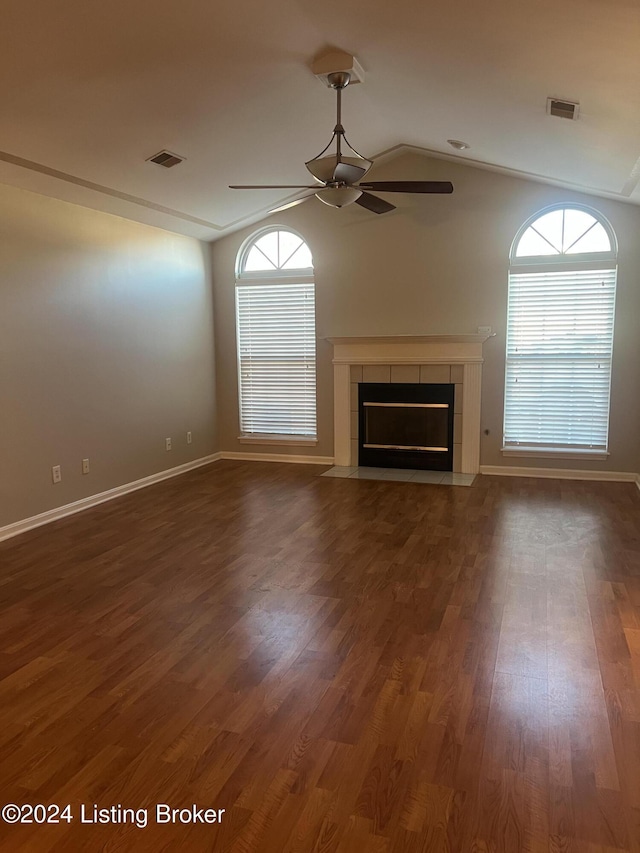 unfurnished living room featuring dark hardwood / wood-style flooring, plenty of natural light, a tile fireplace, and lofted ceiling