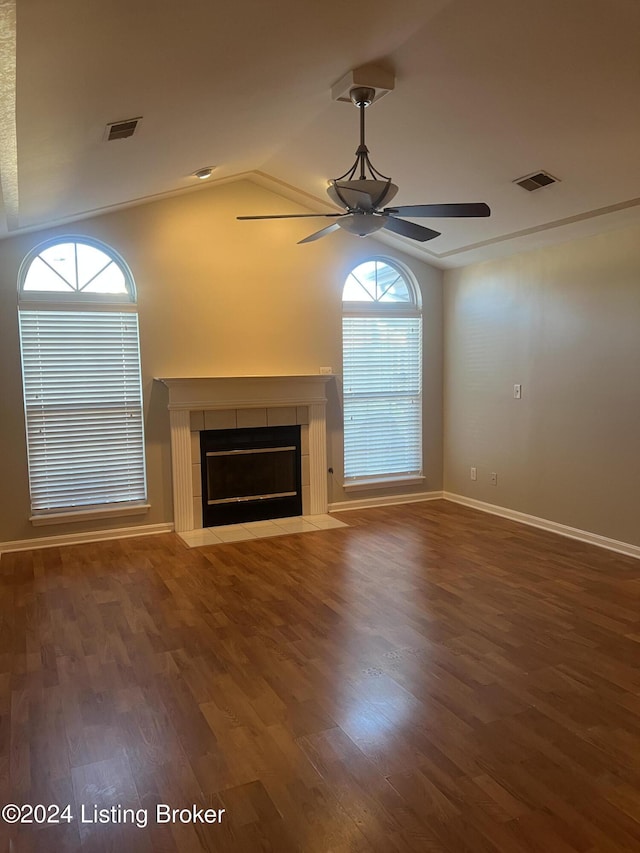 unfurnished living room with dark hardwood / wood-style floors, vaulted ceiling, ceiling fan, and a tiled fireplace