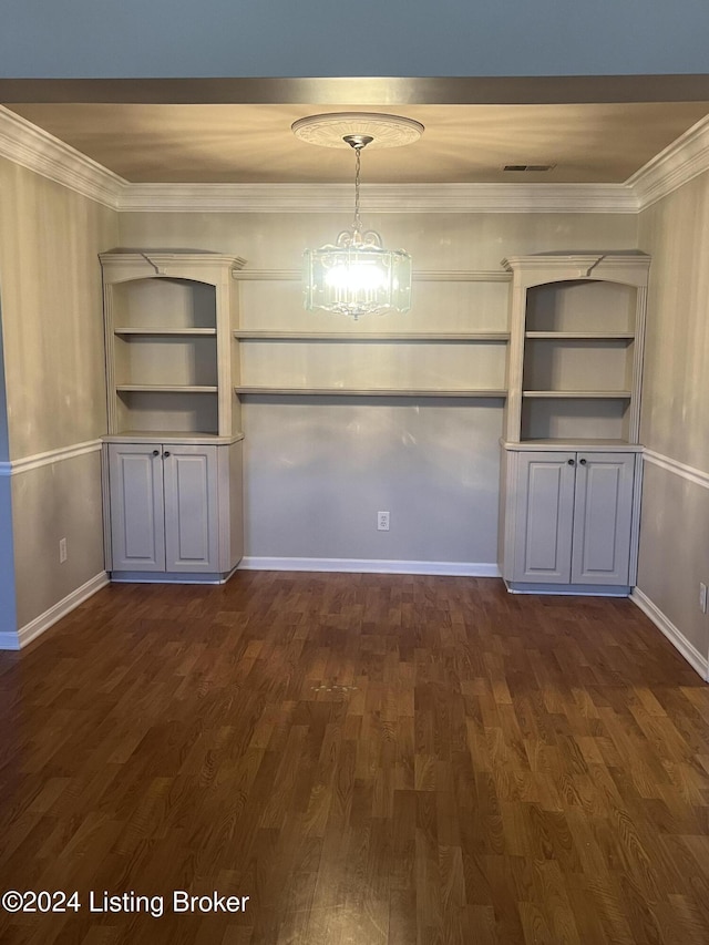 unfurnished dining area with a notable chandelier, built in features, dark wood-type flooring, and ornamental molding