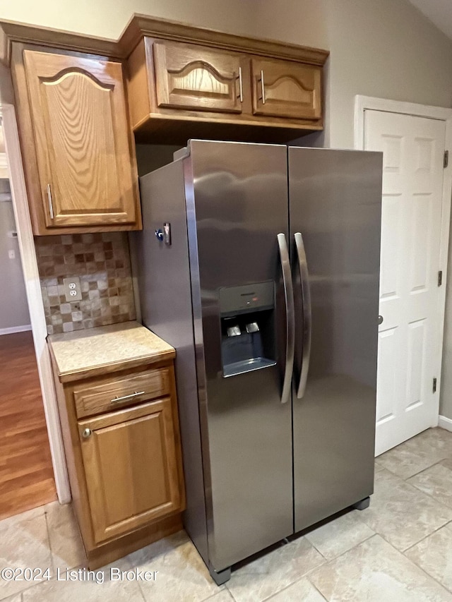 kitchen featuring vaulted ceiling, light hardwood / wood-style floors, stainless steel fridge with ice dispenser, and tasteful backsplash