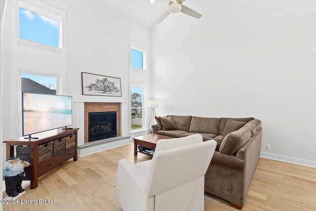 living room featuring ceiling fan, light wood-type flooring, and a high ceiling