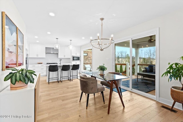 dining space featuring light wood-type flooring, sink, and an inviting chandelier