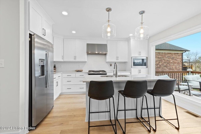 kitchen featuring white cabinets, stainless steel appliances, wall chimney exhaust hood, and sink