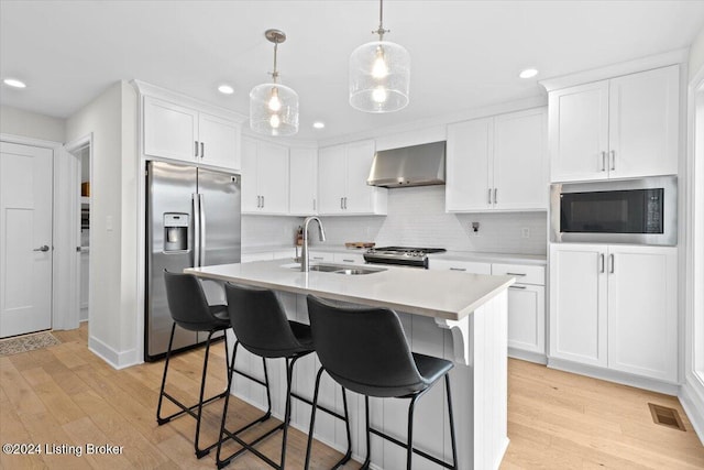 kitchen featuring white cabinets, wall chimney exhaust hood, light hardwood / wood-style floors, and stainless steel appliances