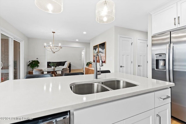 kitchen with sink, white cabinets, stainless steel appliances, and decorative light fixtures