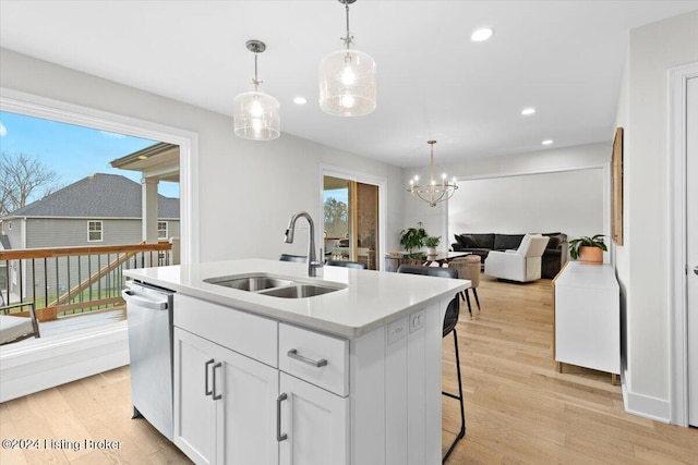 kitchen featuring white cabinets, a center island with sink, sink, stainless steel dishwasher, and light hardwood / wood-style floors