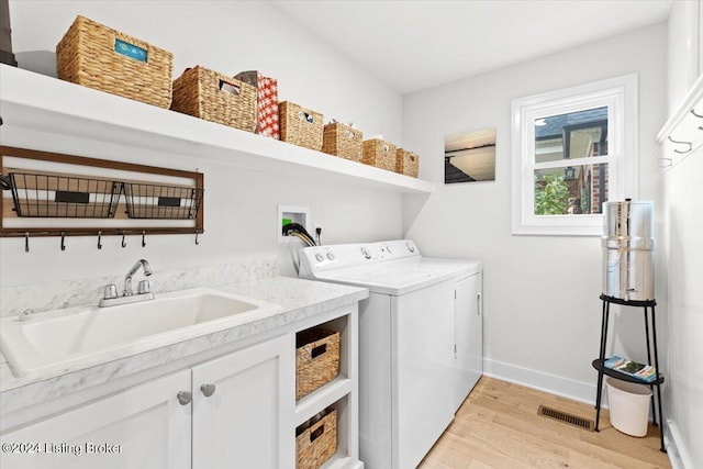 laundry area with cabinets, independent washer and dryer, light hardwood / wood-style flooring, and sink