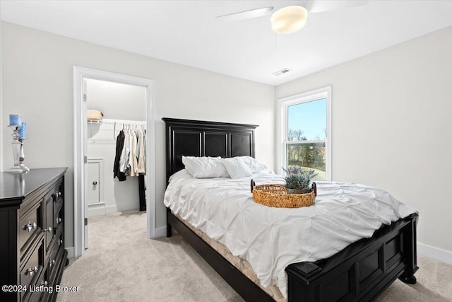 carpeted bedroom featuring ceiling fan, a walk in closet, and a closet