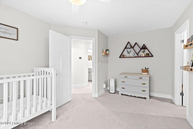 bedroom featuring ceiling fan, light carpet, and a crib