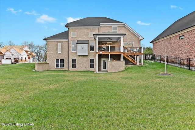 rear view of property featuring a wooden deck, ceiling fan, and a yard