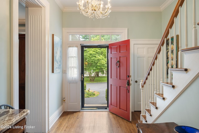 entrance foyer featuring ornamental molding, a notable chandelier, and hardwood / wood-style flooring