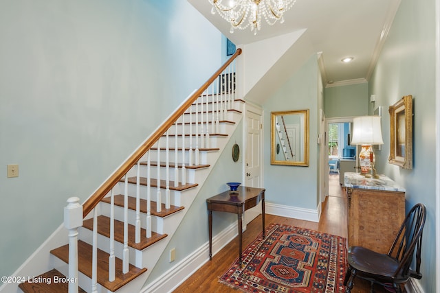 stairway with a chandelier, wood-type flooring, and ornamental molding