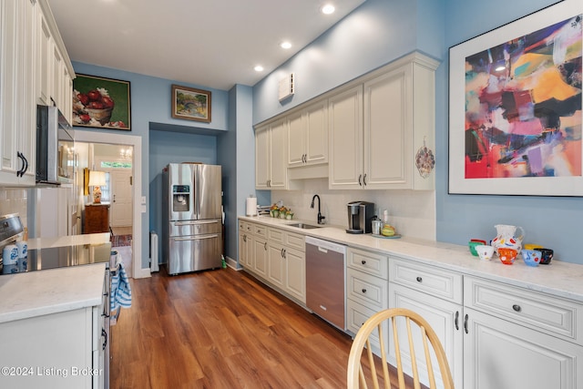 kitchen with light stone countertops, sink, dark hardwood / wood-style flooring, decorative backsplash, and appliances with stainless steel finishes