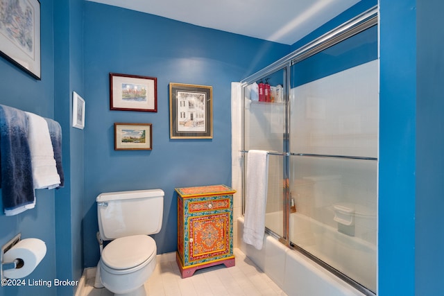 bathroom with tile patterned floors, toilet, and shower / bath combination with glass door