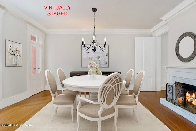 dining room with crown molding, a fireplace, wood-type flooring, and a notable chandelier