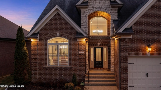 view of exterior entry with a garage, stone siding, and brick siding